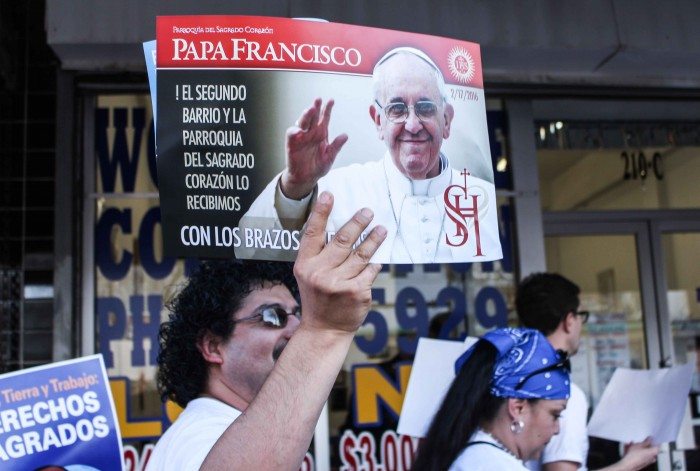 A man holds a welcome sign for Pope Francis. (Maria Esquinca)